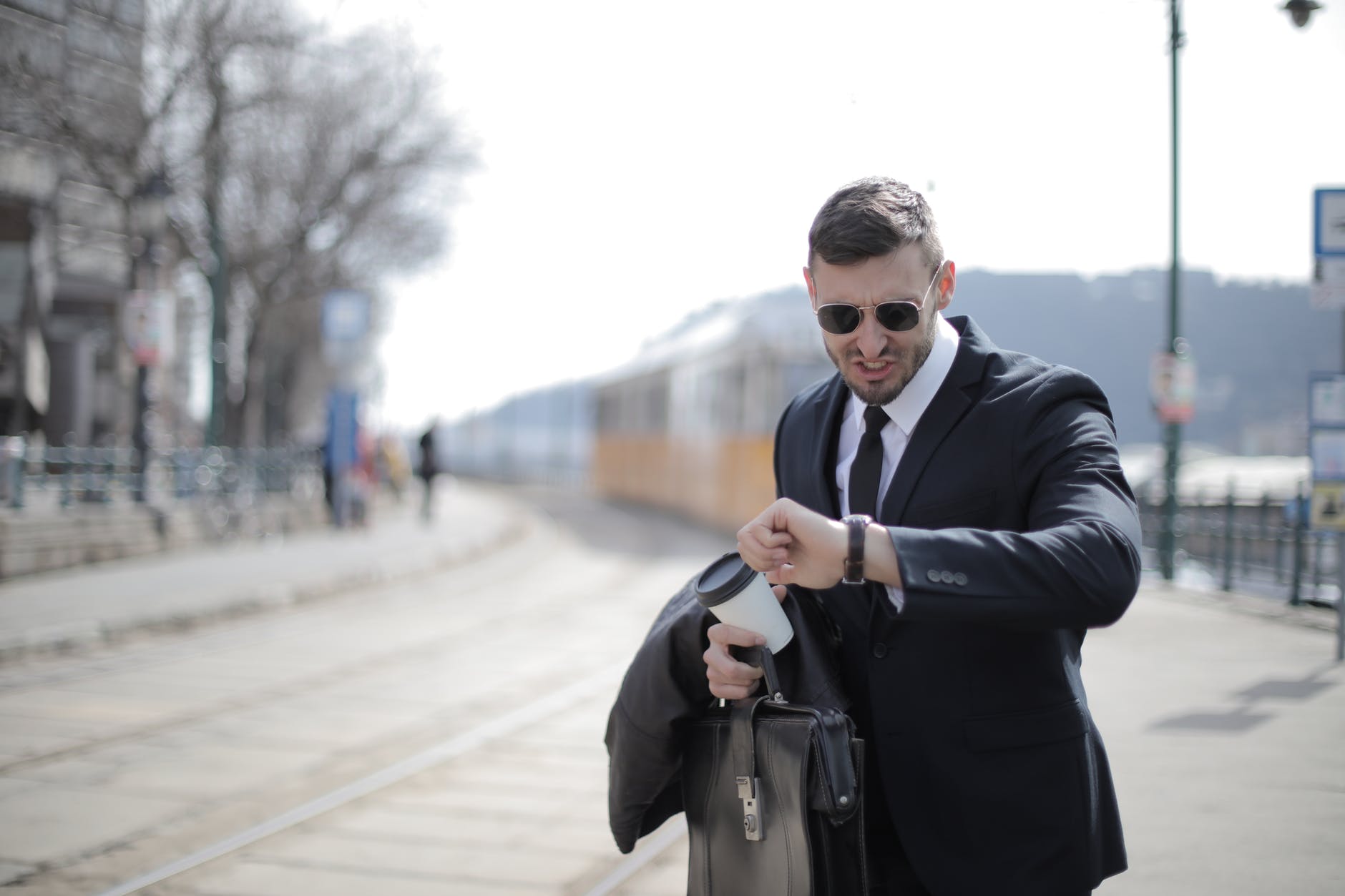 man in black suit jacket holding black leather bag